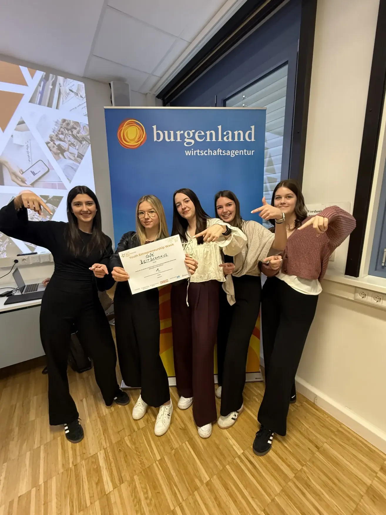 Fünf Frauen posieren für ein Foto, halten eine Urkunde in der Hand, vor einem Banner mit der Aufschrift Burgenland Wirtschaftsagentur.