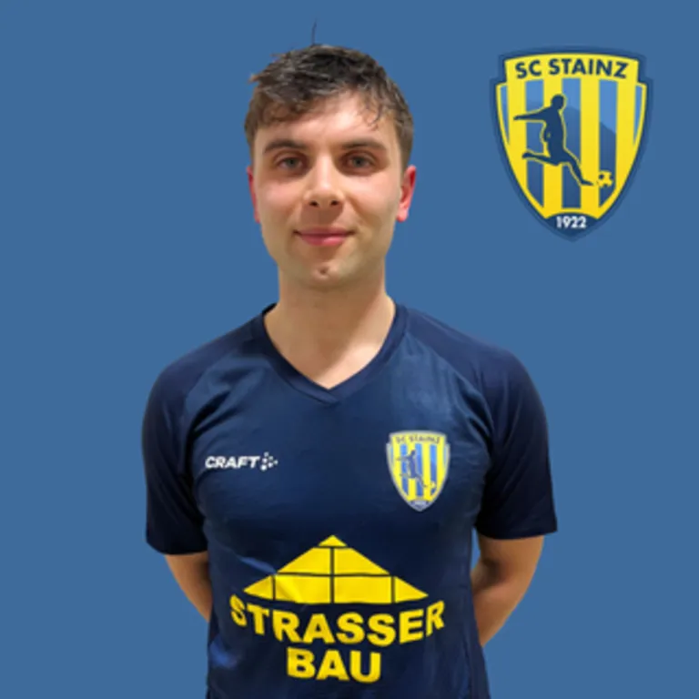 A man in a blue jersey with Strasser Bau written on it stands against a blue background. A SC Stainz logo is next to him.