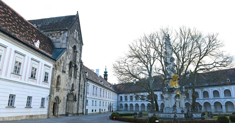 Ein altes europäisches Bauwerk mit einer Statue und einem Brunnen in der Mitte des Innenhofs.