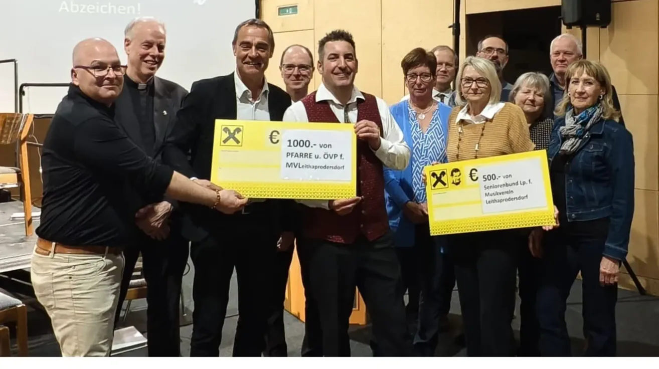 A group of people standing together and smiling, holding yellow checks. Two men in suits holding checks with €1000 and €500 respectively.