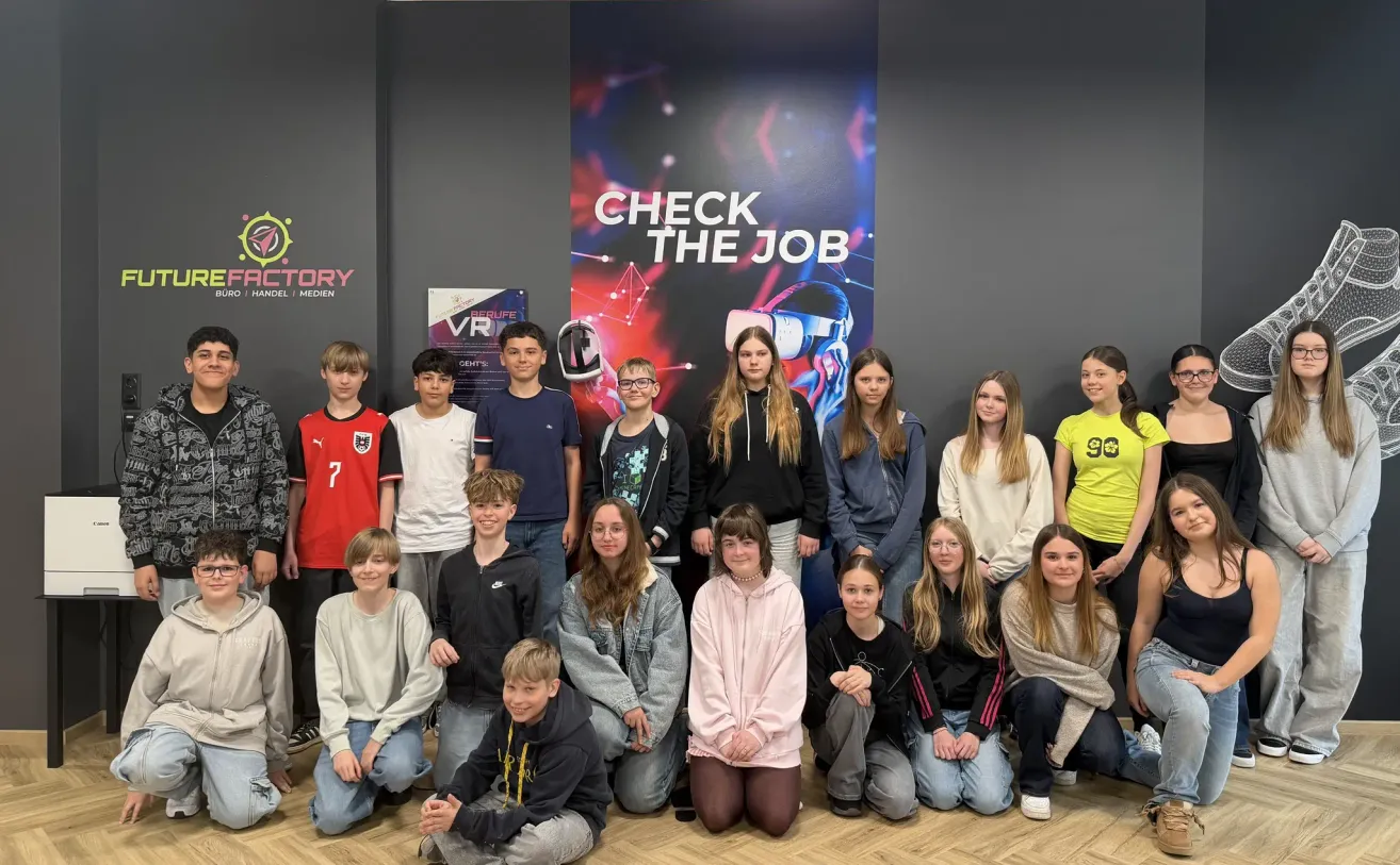 Group photo of students posing in front of a banner that reads 'Check the Job'. The students are sitting and standing in a line, some wearing glasses and sneakers.