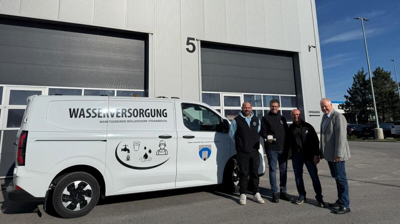 Three men are standing in front of a white van with the words Wasserversorgung on the side, possibly in a parking lot.
