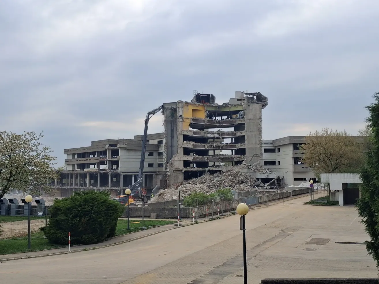 A demolition site with a crane operating on an old building. The building is being torn down, and debris is scattered around.
