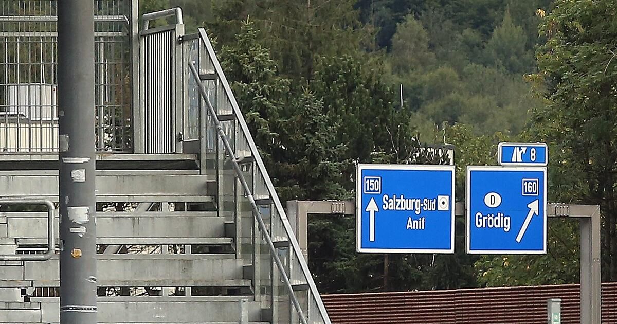 A staircase with a railing leads to a street with two signs. One sign points to Salzburg-South and the other to Grödig.