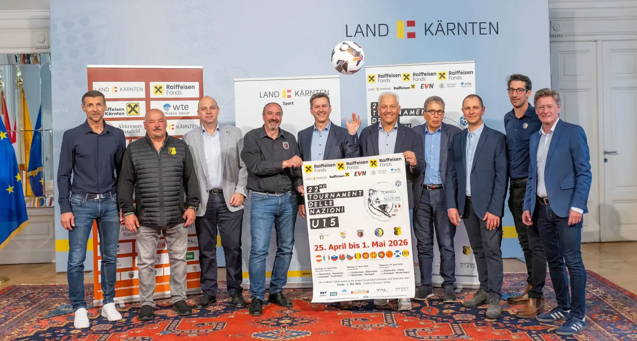 A group of men in suits stands in front of a banner promoting the 2nd National U15 Tournament from April 25 to May 1, 2026. They are smiling and seem to be posing for a photo.