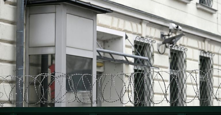 Ein weißes Gebäude mit Überwachungskameras und Stacheldrahtzaun.