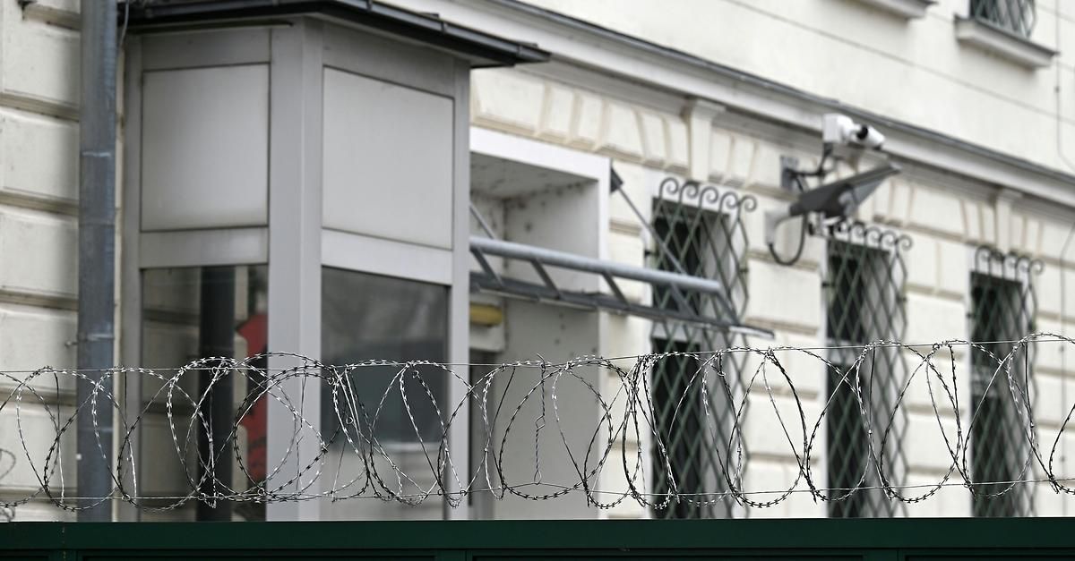 Ein weißes Gebäude mit Überwachungskameras und Stacheldrahtzaun.