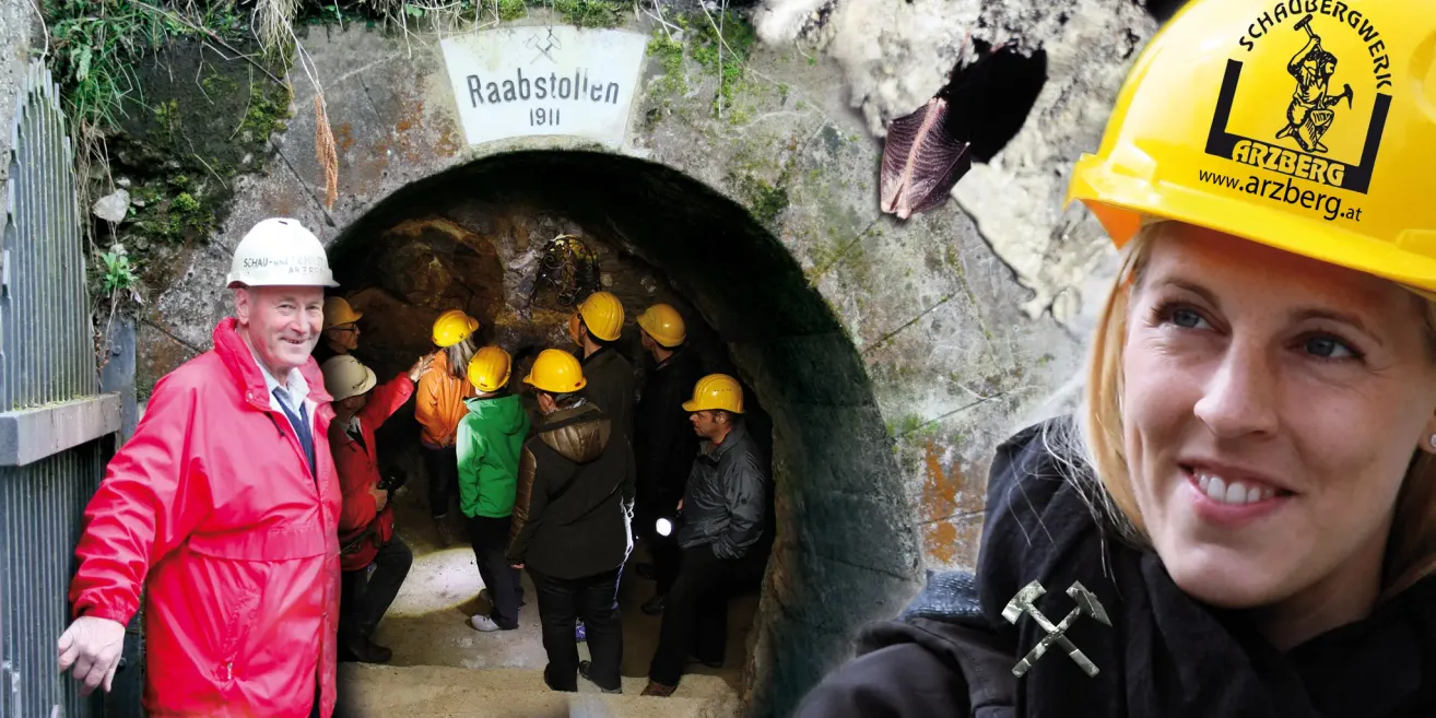 Eine Gruppe von Personen mit Schutzhelmen erkundet einen unterirdischen Tunnel, der mit 'Raabstollen 1911' beschriftet ist.