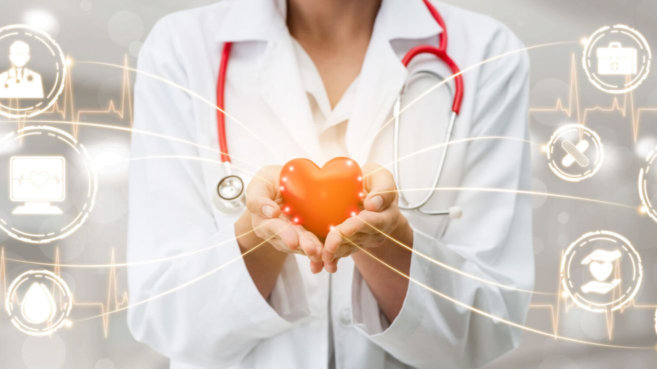 Ein Arzt hält ein leuchtendes orangefarbenes Herz in den Händen, was für Fürsorge und Aufmerksamkeit für die Herzgesundheit steht.