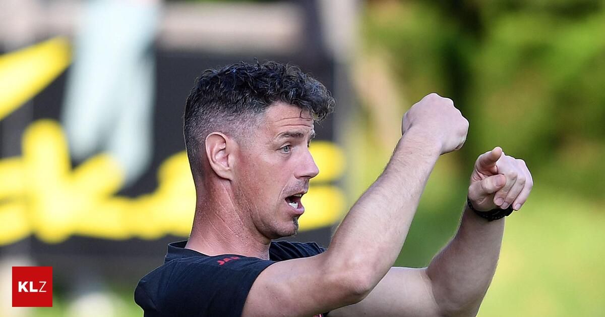 Ein Mann mit Bart, der ein schwarzes T-Shirt trägt, zeigt mit dem Finger nach oben, möglicherweise während eines Fußballtrainings.