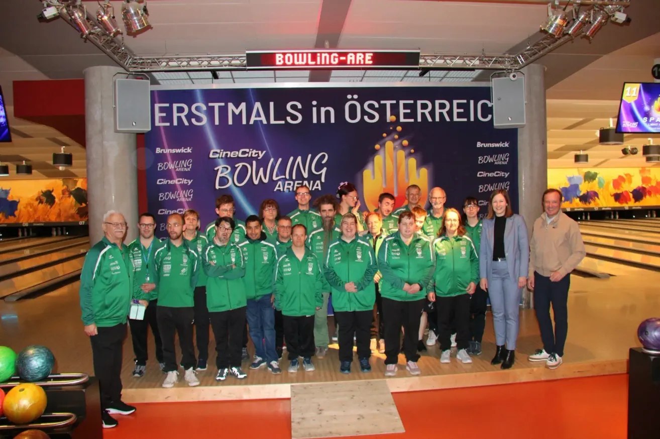 Eine Gruppe von Menschen in grünen Trikots posiert für ein Foto vor einem Bowling-Arena-Banner.
