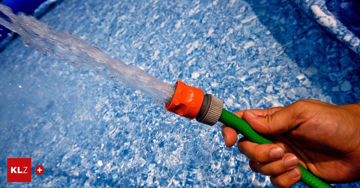 Eine Hand hält einen grünen und orangefarbenen Schlauch, der Wasser in einen blauen Pool mit kleinen Eiswürfeln sprüht.