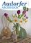 Ein Zeitschriftencover mit einem Strauß aus lila und weißen Tulpen und Narzissen, mit Osterdekorationen wie einem hölzernen Hasen und Ei.