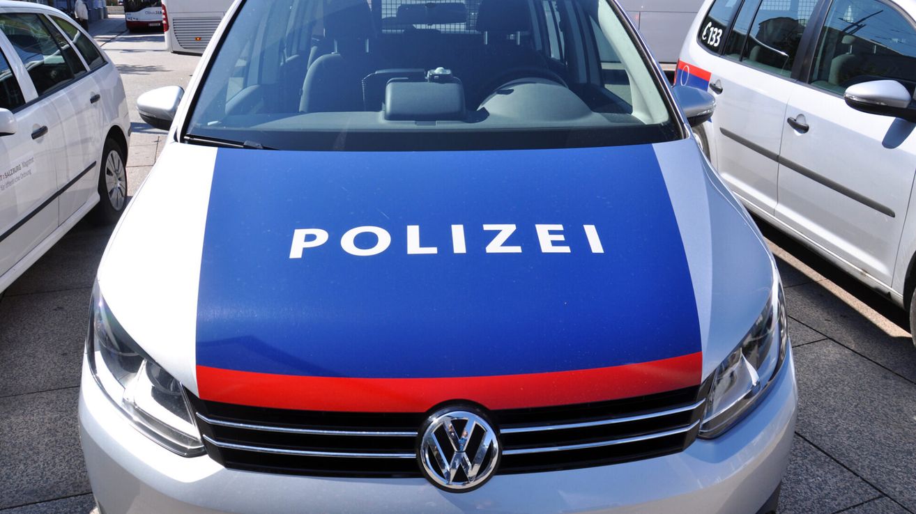 Ein Polizeiauto mit dem Wort 'POLIZEI' auf der vorderen Motorhaube. Es hat eine blau-rote Farbgebung.