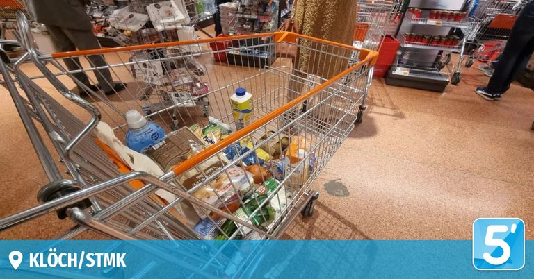 Ein Supermarktregal mit einem vollen Einkaufswagen, gefüllt mit verschiedenen Lebensmitteln, darunter Brot, Pommes Frites und eine Flasche Saft.