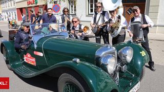 Eine Band spielt Instrumente vor einem alten grünen Auto. Das Auto hat einen Aufkleber mit der Aufschrift Meistermark.