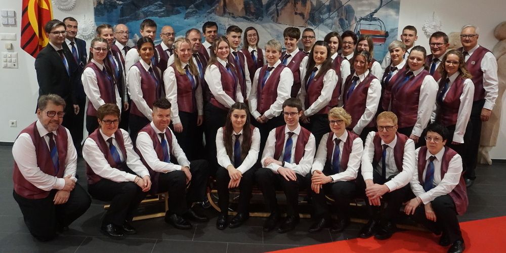 Eine Gruppe von Menschen, die passende Westen und Krawatten tragen, posiert vor einer Wandmalerei für ein Foto.