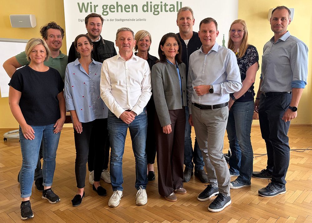 A group of people are posing for a photo in front of a banner that says 'Wir gehen digital'.