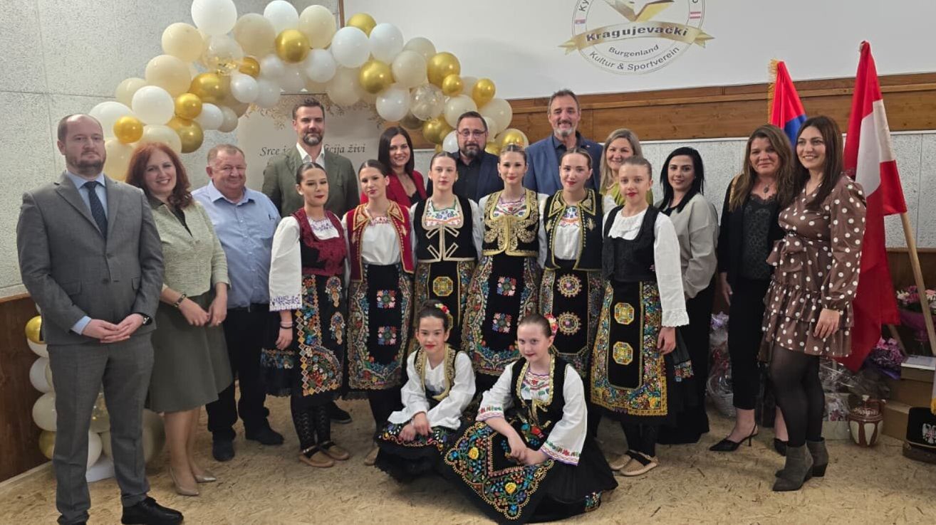 Eine Gruppe von Menschen in traditioneller Kleidung posiert für ein Foto vor einem Hintergrund mit Luftballons.