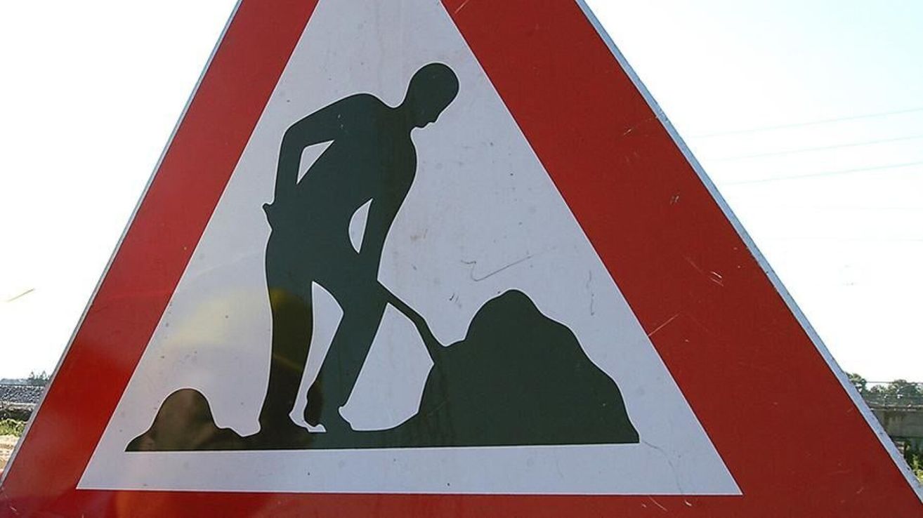 Ein dreieckiges Straßenschild zeigt eine Silhouette eines Mannes, der mit einer Schaufel gräbt. Das Schild hat einen roten Rand und einen weißen Hintergrund.