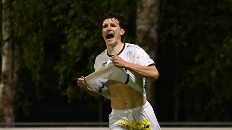 Ein Fußballspieler feiert einen jubelnden Sieg auf einem Nachtfeld, sein Hemd teilweise zerrissen.