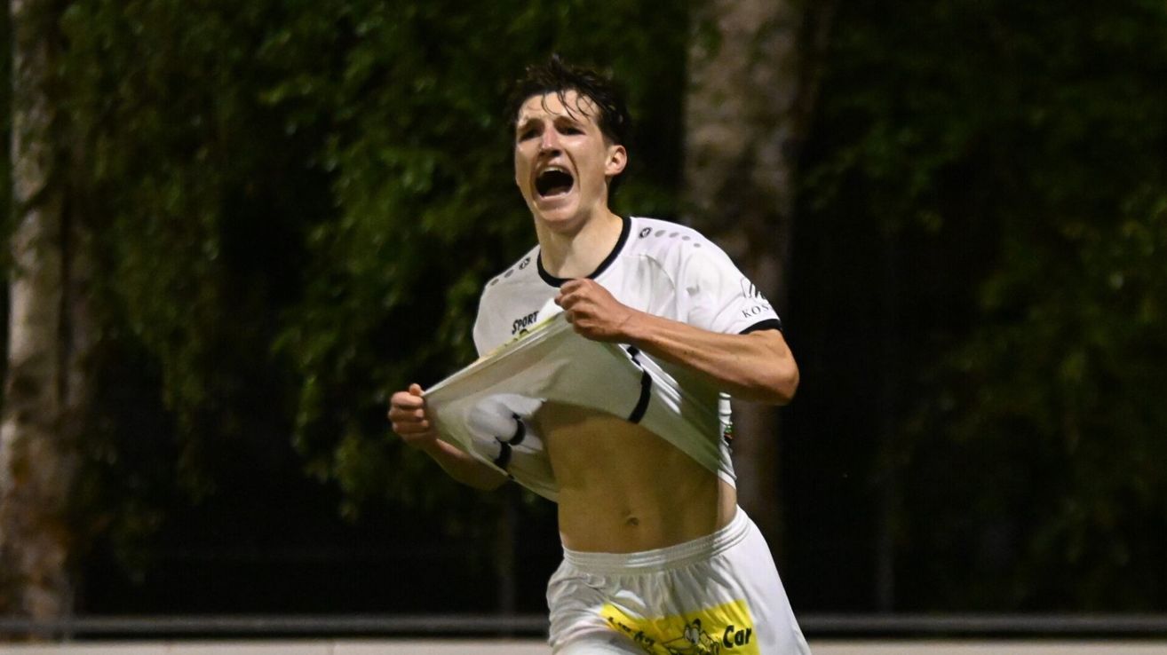 Ein Fußballspieler feiert einen jubelnden Sieg auf einem Nachtfeld, sein Hemd teilweise zerrissen.