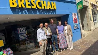 Five people are standing outside a store named Breschan. A sign shows 110 years and a 20% discount.