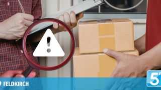 A worker inspects boxes using a magnifying glass with an exclamation mark. A warning is indicated on the package.