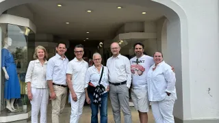Sechs Personen stehen vor dem FRANK-Ladeneingang und posieren lächelnd für ein Foto.