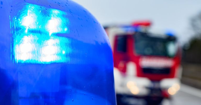 A close-up of a blue emergency vehicle's light bar with a blurred background of another vehicle.