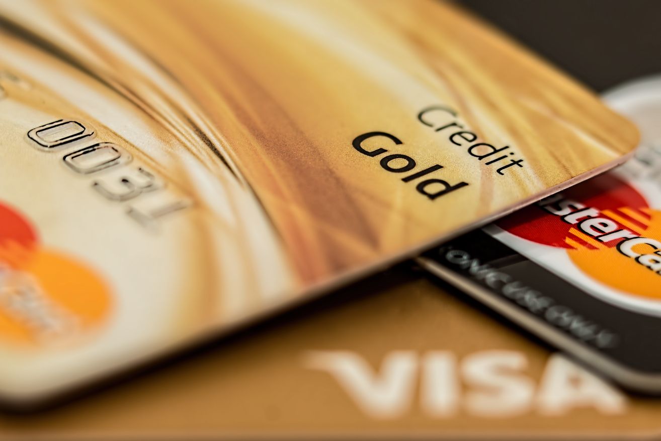 A closeup of a golden credit card labeled 'Gold' with a Visa card partially visible underneath.