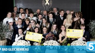 Gruppenfoto von Menschen mit gelben Bändern und Schildern, die Blumen und Geld halten. Sie lächeln und posieren für ein Foto. Das Foto hat ein Wasserzeichen mit der Aufschrift 'SCHENBERG'.