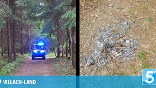 Ein Krankenwagen fährt mit blauen Lichtern auf einem Waldweg. In der Nähe ist ein Feuerstelle mit Asche und verkohltem Holz zu sehen.