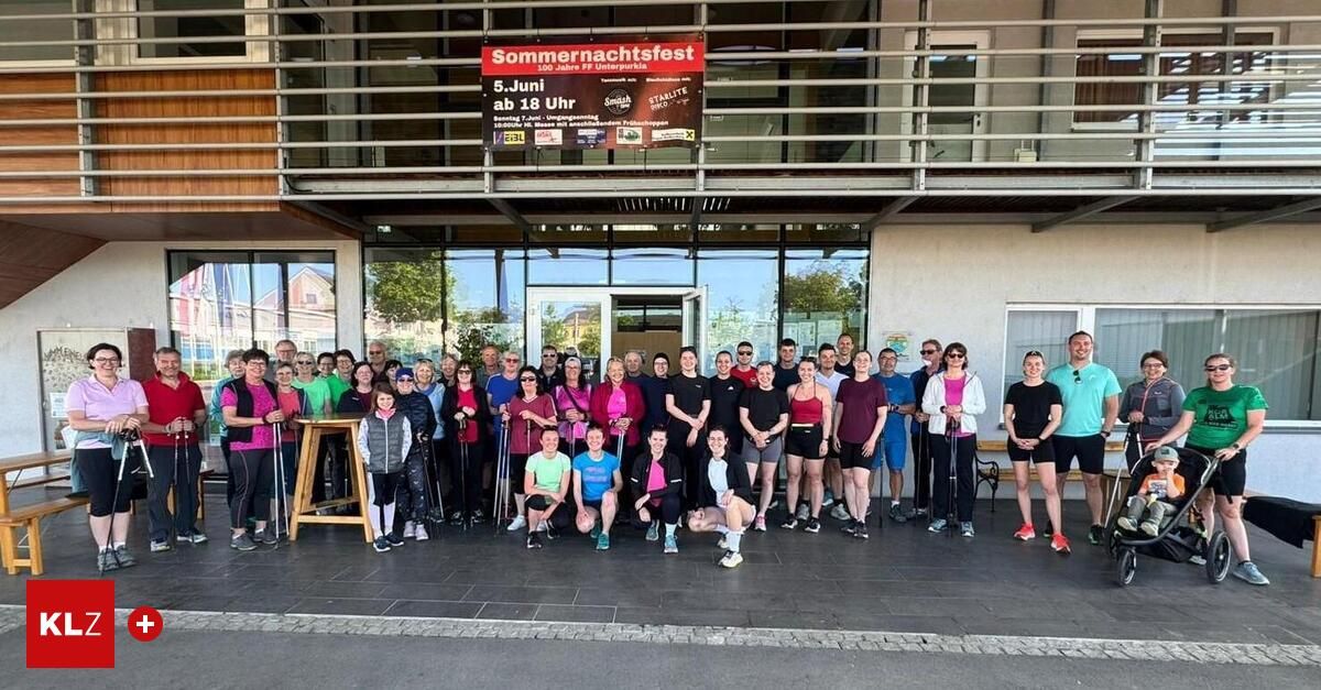 Eine große Gruppe von Menschen steht vor einem Gebäude und hält Stöcke, wahrscheinlich für eine Sportveranstaltung. Ein Banner oben zeigt 'Sommernachtsfest'.