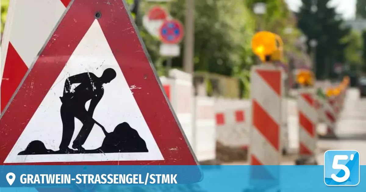 Ein Warnschild zeigt eine Silhouette eines Arbeiters mit einer Schaufel. Es ist rot mit einem weißen Dreieck. Das Schild ist teilweise verschwommen mit dem Text STRASSESNGEL/STMK.