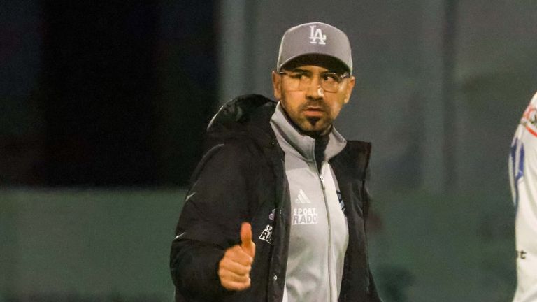 Ein Mann in einer schwarzen Jacke mit 'LA'-Mütze gibt ein Daumen hoch. Die Jacke hat 'SPORT' und 'RADO' auf der Vorderseite.