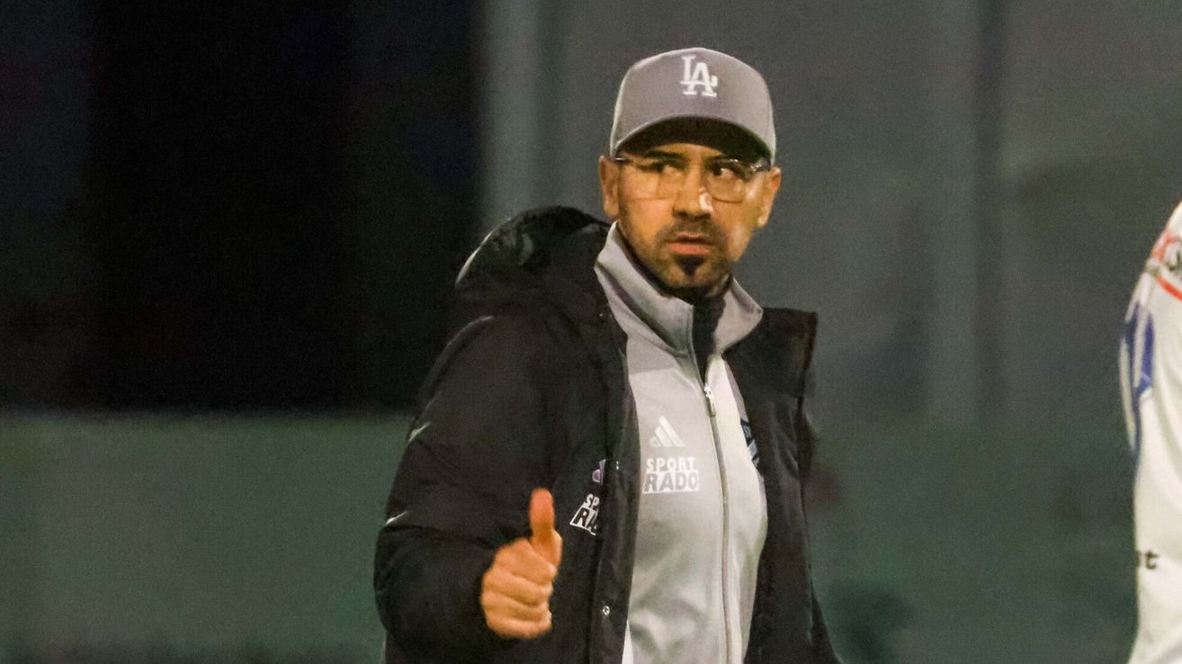 Ein Mann in einer schwarzen Jacke mit 'LA'-Mütze gibt ein Daumen hoch. Die Jacke hat 'SPORT' und 'RADO' auf der Vorderseite.