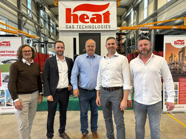 Five men stand in front of a banner advertising HEAT GAS TECHNOLOGIES. They all wear professional attire, possibly for a work event.