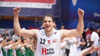 Ein Basketballspieler feiert den Sieg vor einer Menschenmenge. Er trägt ein weißes Trikot mit der Nummer 22 und dem Wort Heffe Helfen.