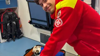 Ein Mann in einem roten und gelben Anzug lächelt und überprüft einen medizinischen Beutel in einem Krankenwagen.