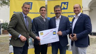 Vier Männer stehen vor einem gelben Banner und halten ein weißes Papier mit 'Ferienaktion 2023' darauf, einer der Männer hält einen Scheck über 1.937,10 Euro.