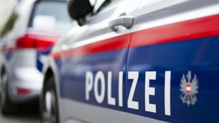 Eine Nahaufnahme der Seite eines Polizeiwagens mit dem Wort Polizei in Weiß auf blauem Hintergrund.
