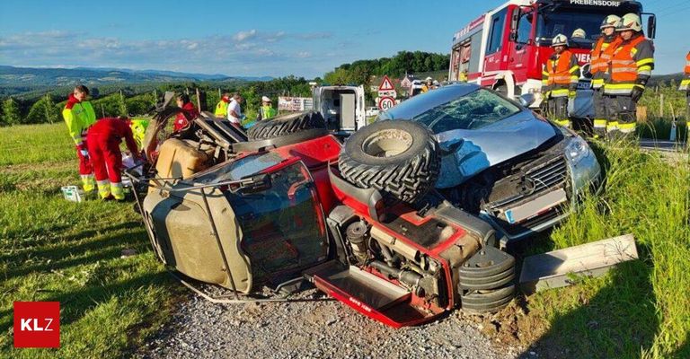 Ein Autounfall mit zwei Fahrzeugen auf einem Schotterweg. Ein Fahrzeug ist umgekippt, und ein anderes ist beschädigt. Feuerwehrwagen sind anwesend, und Leute haben sich versammelt.