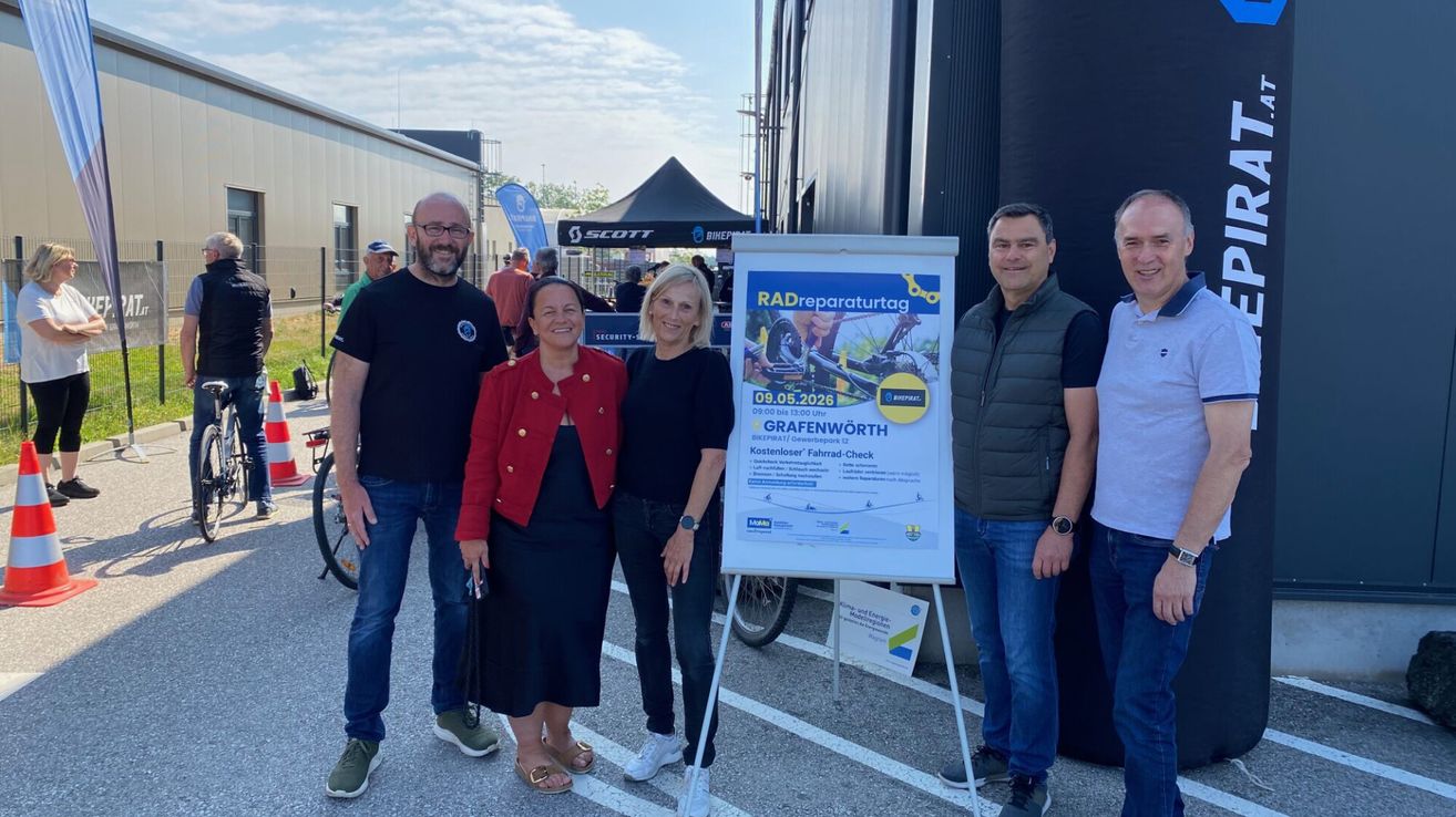 Five people are standing outside with a sign that says Radreperaturtag, a bike repair day, scheduled for May 9, 2026, at Grafenwörth.