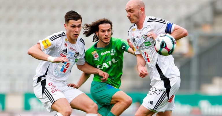 Three soccer players engage in a match. A player in green chases the ball, while two others in white attempt to intercept.