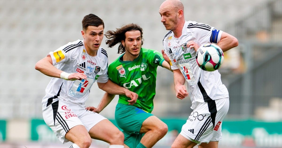 Three soccer players engage in a match. A player in green chases the ball, while two others in white attempt to intercept.