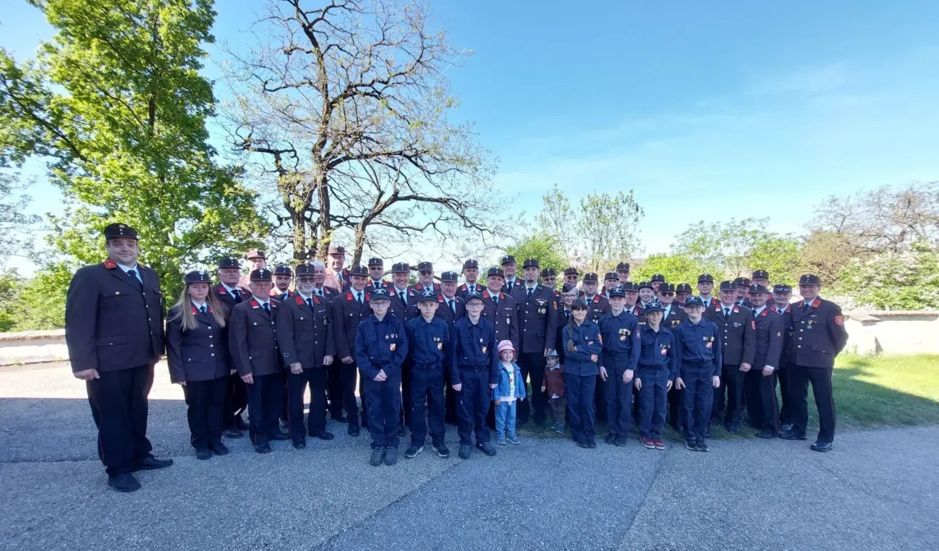 Eine Gruppe uniformierter Personen, möglicherweise eine Polizei- oder Militäreinheit, posiert mit mehreren Kindern vor einem Baum für ein Foto.