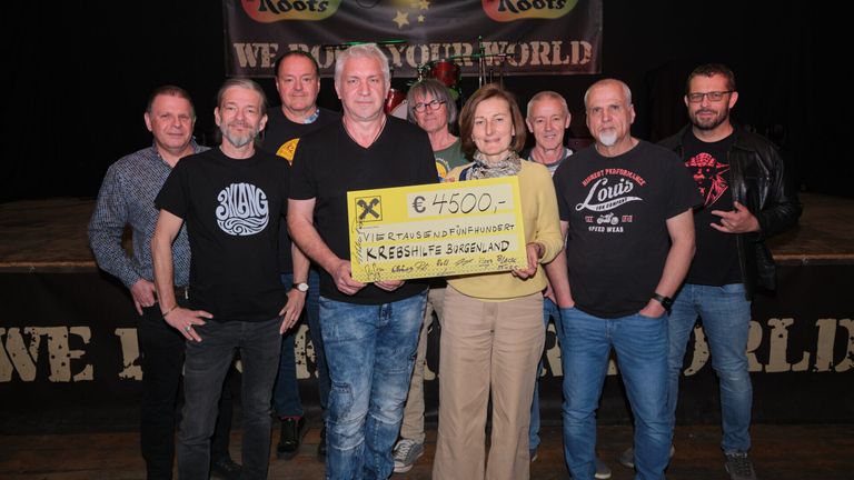 Eine Gruppe von Menschen vor einem Roots-Banner hält einen Scheck über 4500 Euro für Krebshilfe Burgenland.