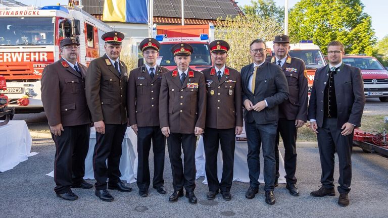 Sechs Männer stehen für ein Foto zusammen. Fünf in Militäruniformen, einer im Anzug. Hinter ihnen sind Rettungsfahrzeuge.