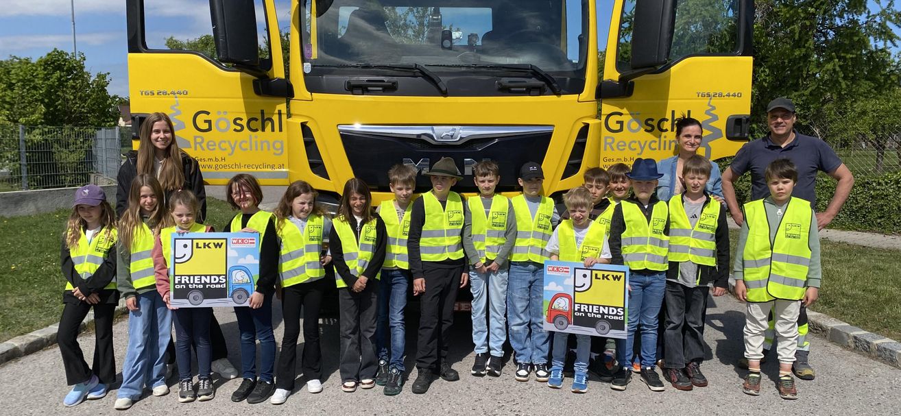 Group of children in reflective vests standing in front of a yellow recycling truck with the logo LKW Friends on the Road.